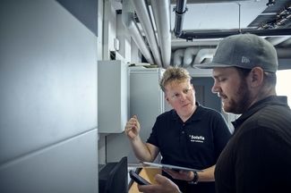 Niels Hintermann steht im Keller vor dem Batteriespeicher und sieht die Daten auf seinem Handy an